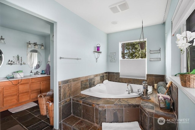 bathroom with tiled tub and vanity