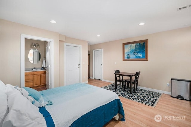 bedroom featuring ensuite bath, light hardwood / wood-style flooring, and sink