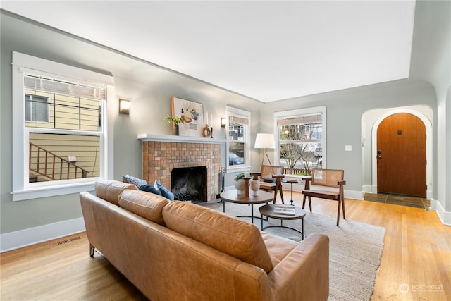 living room with a brick fireplace and light hardwood / wood-style flooring