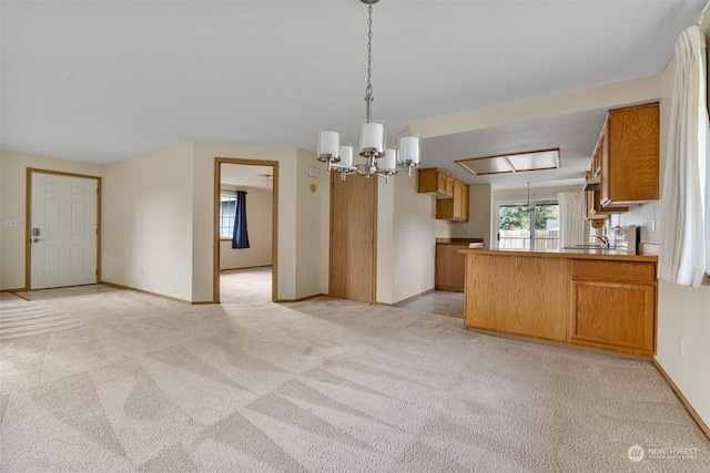 kitchen with pendant lighting, light colored carpet, kitchen peninsula, and an inviting chandelier