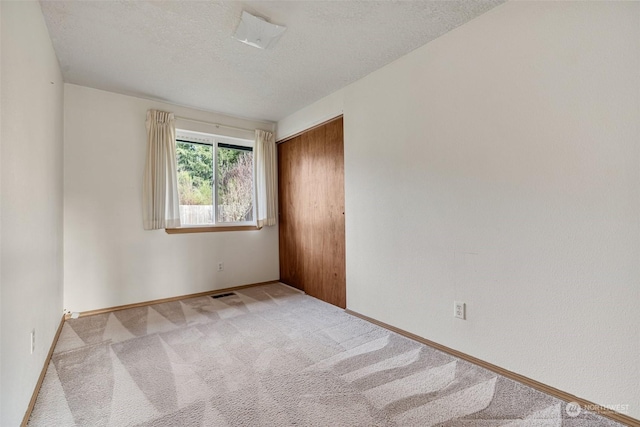 carpeted empty room with a textured ceiling