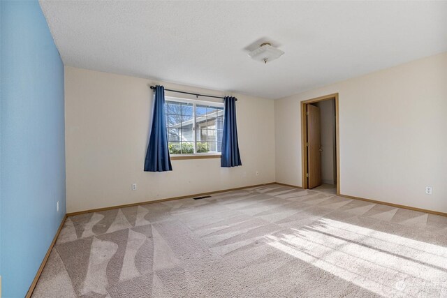 unfurnished room with light colored carpet and a textured ceiling