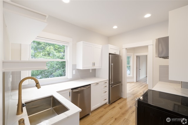 kitchen featuring backsplash, white cabinets, sink, light wood-type flooring, and appliances with stainless steel finishes