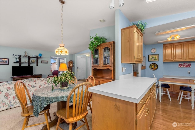 kitchen with lofted ceiling, decorative light fixtures, a center island, and light wood-type flooring