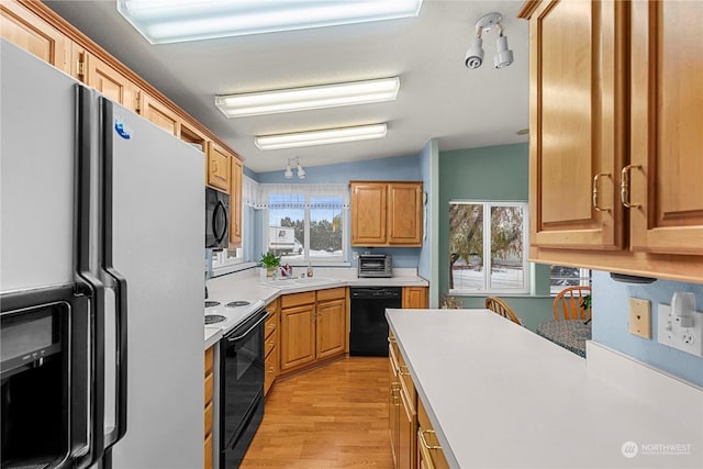 kitchen featuring sink, vaulted ceiling, light hardwood / wood-style flooring, and black appliances