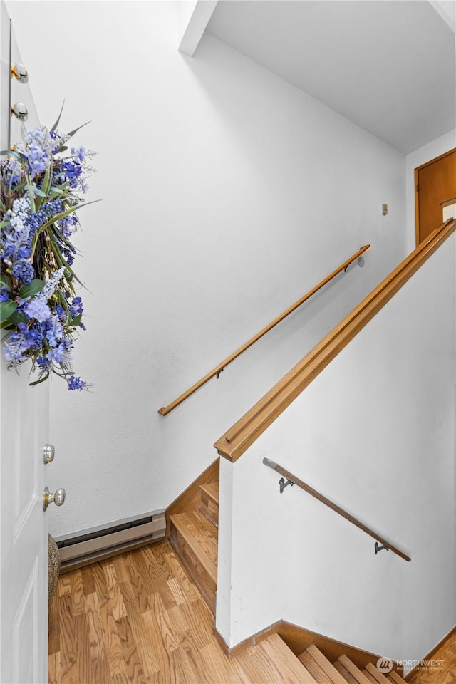 stairway with hardwood / wood-style flooring and a baseboard heating unit