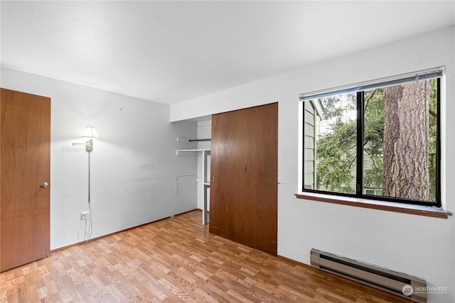 spare room featuring baseboard heating and light hardwood / wood-style flooring