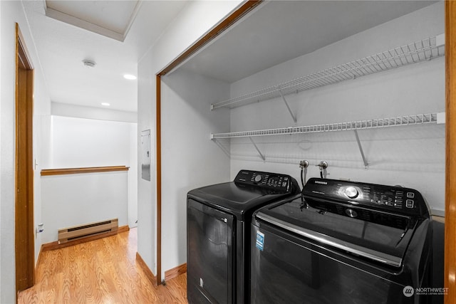 clothes washing area with baseboard heating, independent washer and dryer, and hardwood / wood-style flooring