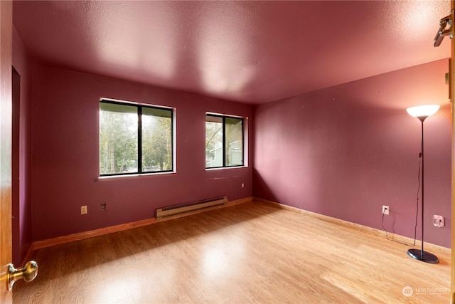 spare room with a baseboard radiator, a textured ceiling, and wood-type flooring