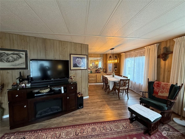 living room featuring hardwood / wood-style floors, a textured ceiling, wooden walls, and a notable chandelier