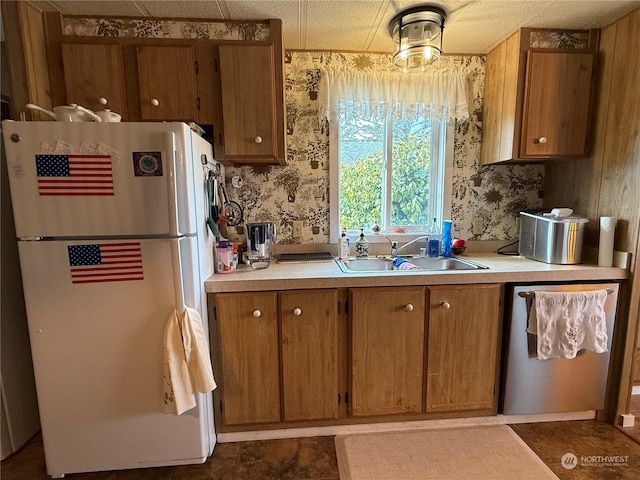 kitchen with dishwasher, a textured ceiling, white fridge, and sink