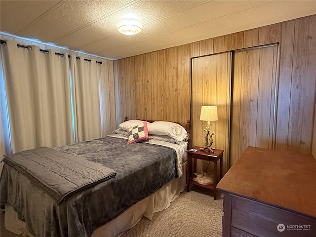 carpeted bedroom with a textured ceiling, a closet, and wooden walls