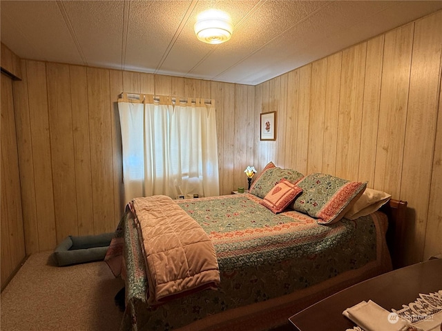 bedroom with carpet flooring, wood walls, and a textured ceiling