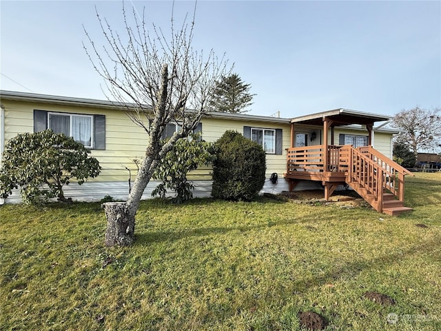 rear view of property featuring a lawn and a wooden deck