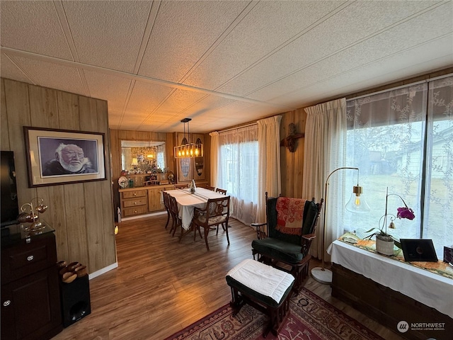 living area featuring a textured ceiling, wooden walls, a notable chandelier, and hardwood / wood-style flooring