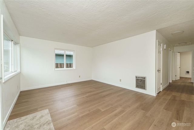 empty room featuring a textured ceiling, hardwood / wood-style flooring, and heating unit