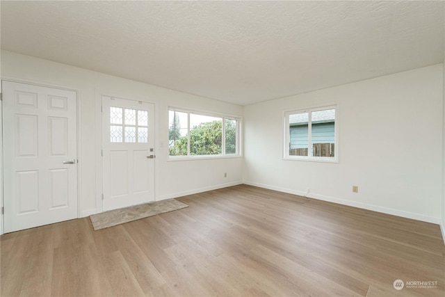 entryway with a textured ceiling and light hardwood / wood-style flooring