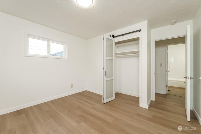 unfurnished bedroom featuring a closet, light hardwood / wood-style floors, and a textured ceiling