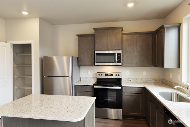 kitchen featuring sink, a center island, stainless steel appliances, light stone counters, and dark hardwood / wood-style flooring