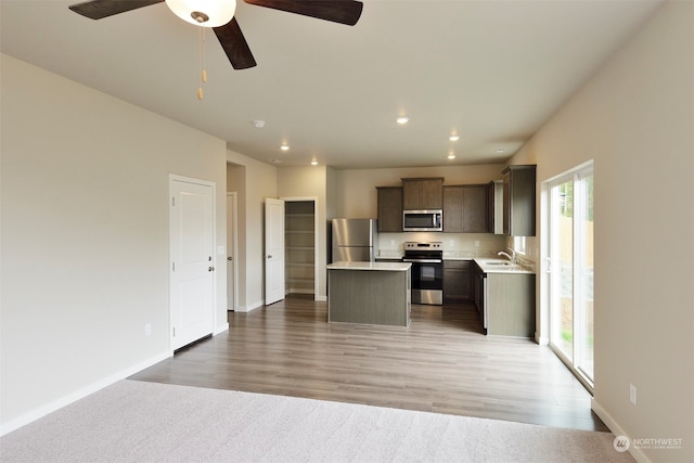 kitchen with ceiling fan, sink, stainless steel appliances, hardwood / wood-style floors, and a kitchen island