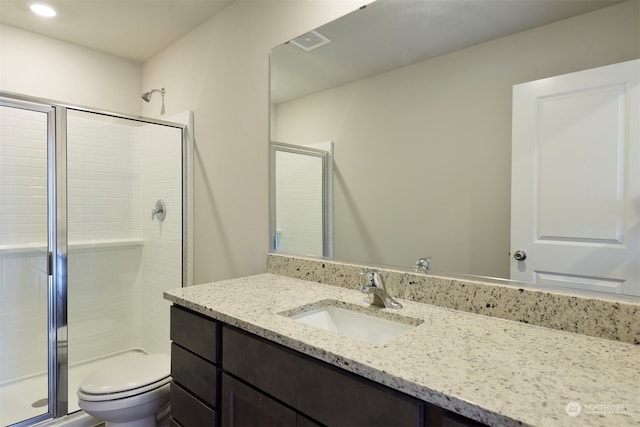 bathroom featuring vanity, toilet, and a shower with shower door