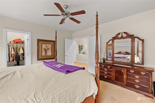 bedroom featuring a walk in closet, ceiling fan, a closet, and light colored carpet