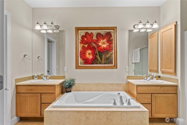 bathroom featuring tile patterned flooring, a relaxing tiled tub, and vanity