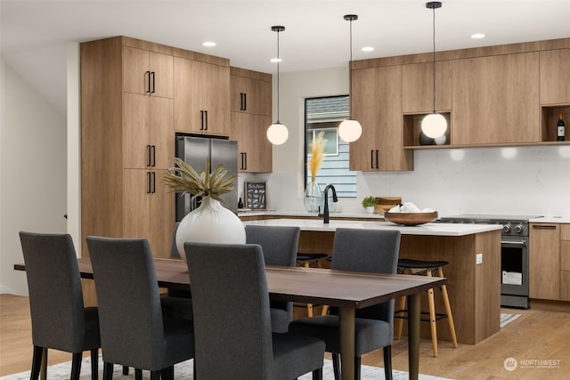 kitchen with decorative backsplash, hanging light fixtures, light hardwood / wood-style floors, and appliances with stainless steel finishes