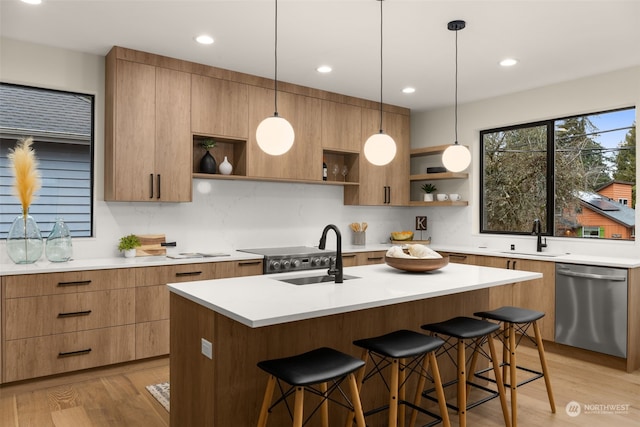 kitchen with dishwasher, light hardwood / wood-style floors, sink, and an island with sink