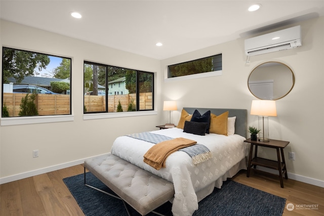 bedroom with an AC wall unit and hardwood / wood-style flooring