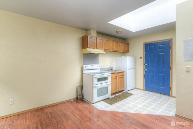 kitchen featuring sink, white appliances, light hardwood / wood-style flooring, and a skylight