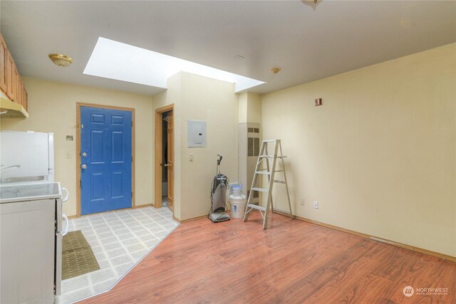 interior space featuring a skylight, light hardwood / wood-style flooring, and electric panel