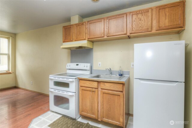 kitchen with white appliances, sink, and light hardwood / wood-style flooring