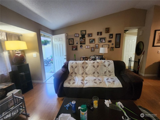 living room with a textured ceiling, vaulted ceiling, and hardwood / wood-style flooring