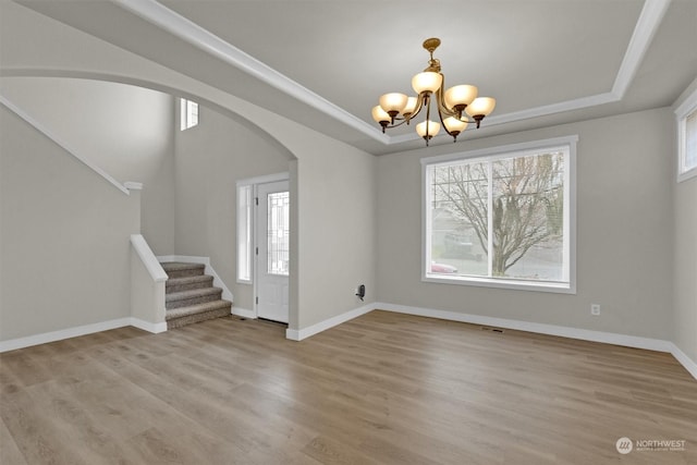 entryway featuring a tray ceiling, a chandelier, and light wood-type flooring