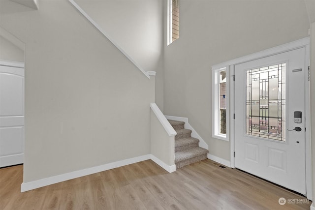 foyer with light wood-type flooring and a towering ceiling