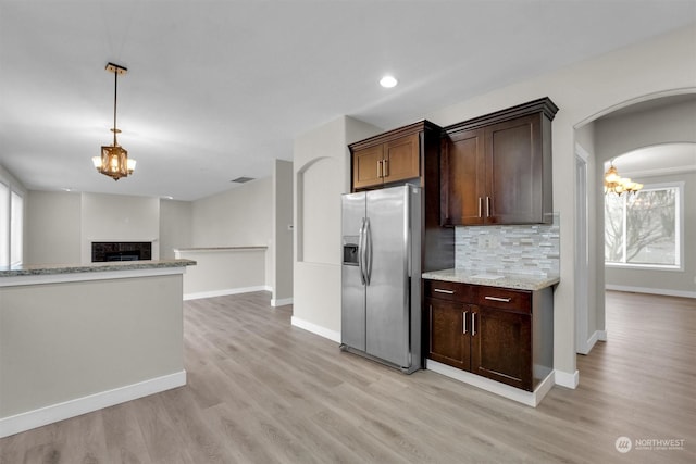 kitchen featuring light hardwood / wood-style flooring, decorative backsplash, stainless steel fridge, light stone counters, and dark brown cabinetry