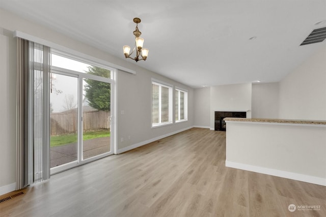 unfurnished living room featuring light wood-type flooring and a chandelier