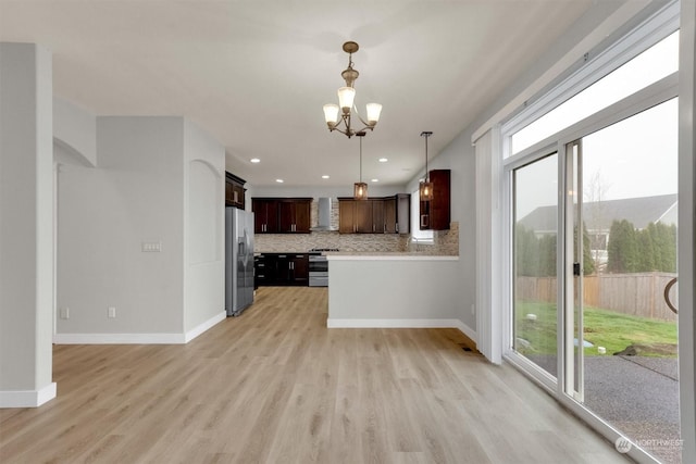 kitchen with a healthy amount of sunlight, pendant lighting, stainless steel appliances, and light hardwood / wood-style floors