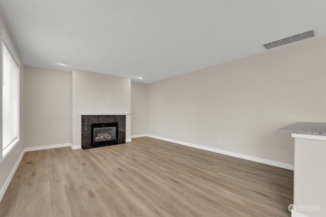 unfurnished living room featuring a fireplace and light hardwood / wood-style flooring