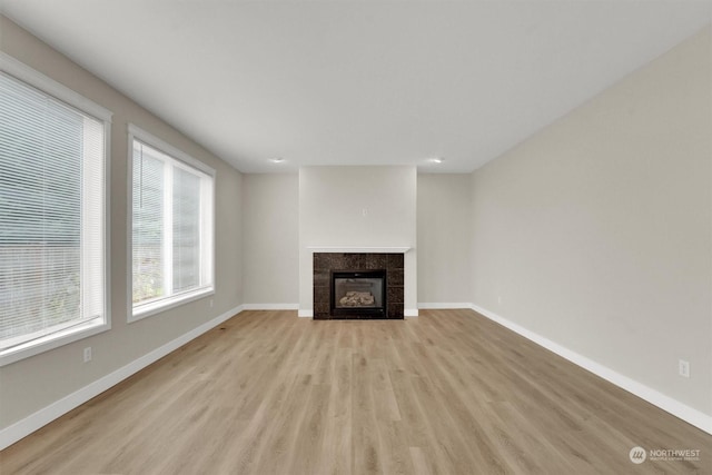 unfurnished living room with light hardwood / wood-style floors and a tiled fireplace