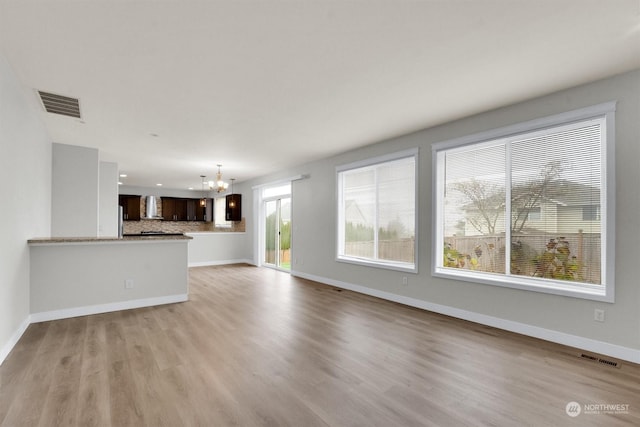 unfurnished living room with light hardwood / wood-style flooring and a notable chandelier