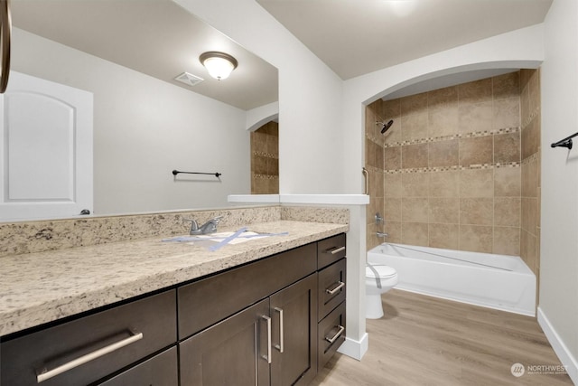 full bathroom with vanity, hardwood / wood-style flooring, toilet, and tiled shower / bath combo