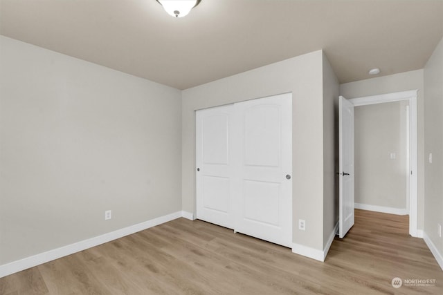 unfurnished bedroom with light wood-type flooring and a closet