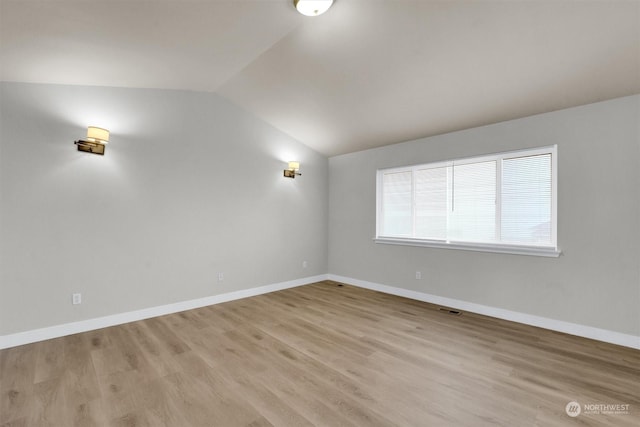 unfurnished room featuring vaulted ceiling and light hardwood / wood-style flooring