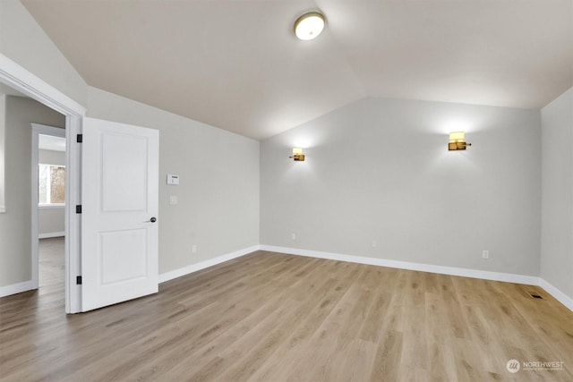 spare room featuring light hardwood / wood-style floors and vaulted ceiling