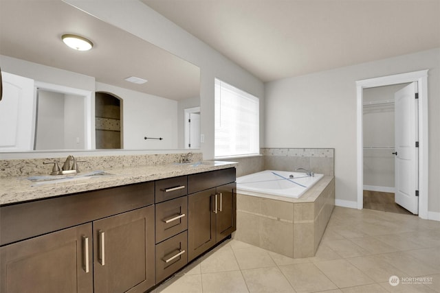 bathroom with tile patterned flooring, vanity, and tiled tub