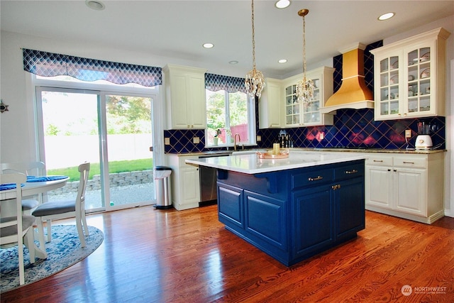 kitchen with decorative backsplash, a kitchen island, light hardwood / wood-style floors, and custom exhaust hood