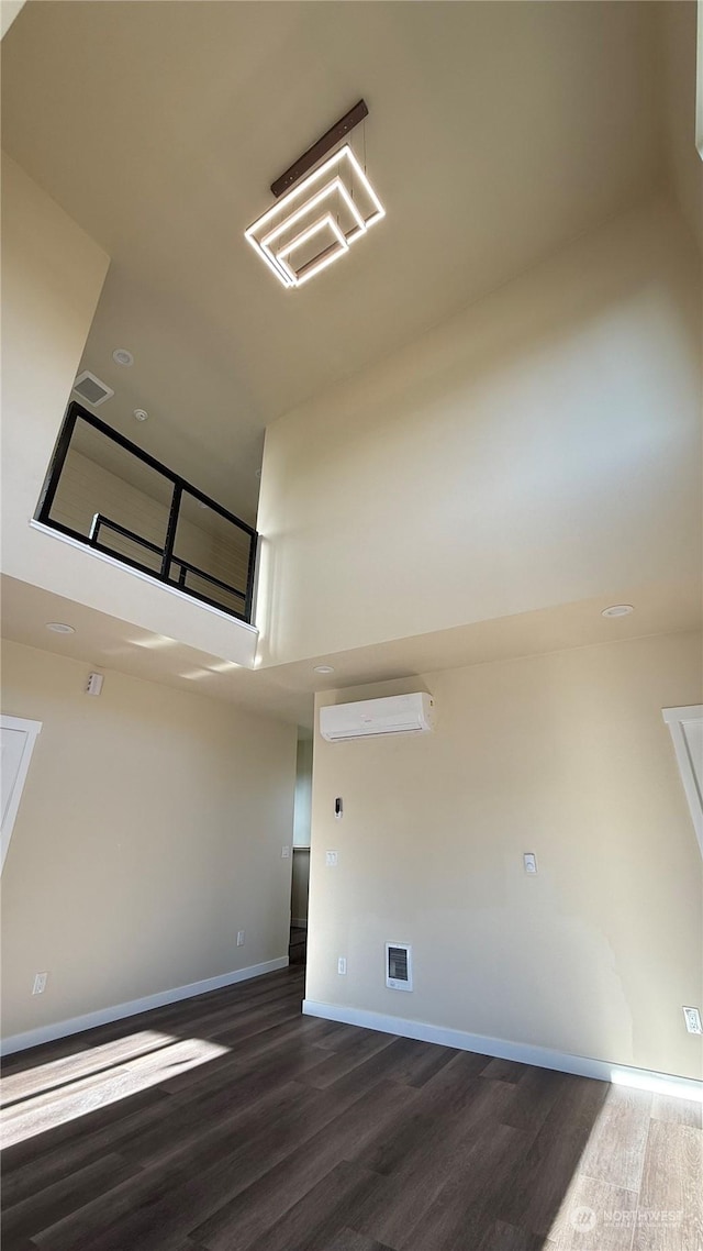 interior space with hardwood / wood-style flooring, a wall mounted air conditioner, and a towering ceiling