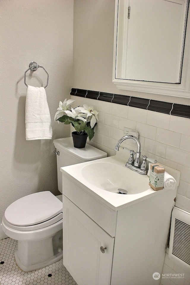 bathroom with tile patterned flooring, vanity, toilet, and tile walls